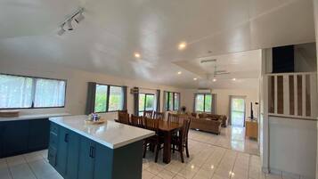 Una cocina amplia con una isla central, comedor con sillas y sala de estar con sofá.