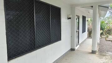 Un pasillo cubierto con pared blanca, cerca metálica y suelo de hormigón.