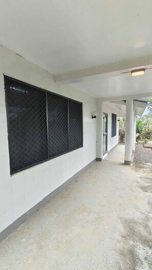 Un pasillo cubierto con pared blanca, cerca metálica y suelo de hormigón.