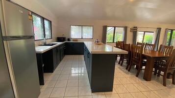 Una cocina amplia con una isla central, muebles oscuros y una zona de comedor con sillas de madera.