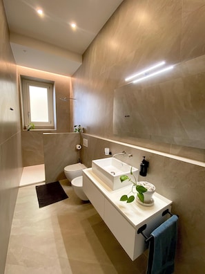 A modern bathroom with a large mirror, a rectangular sink, and a toilet. - Sea & Sun Suite (Cagliari)