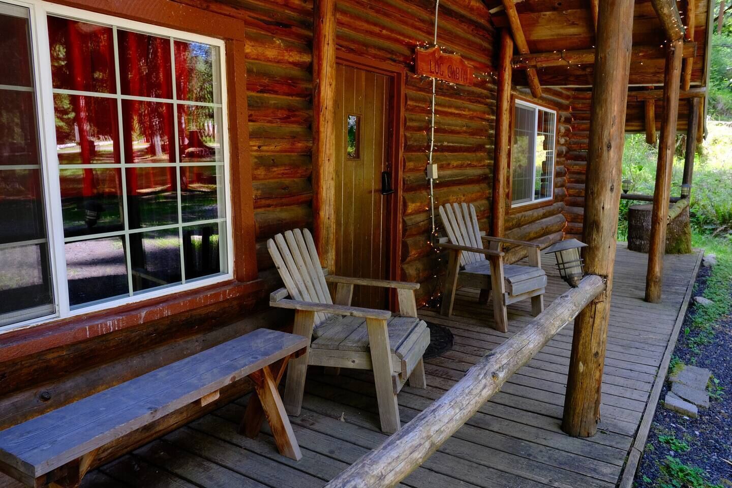 Eine Blockhütte mit Veranda, Holzstühlen und einer Bank.