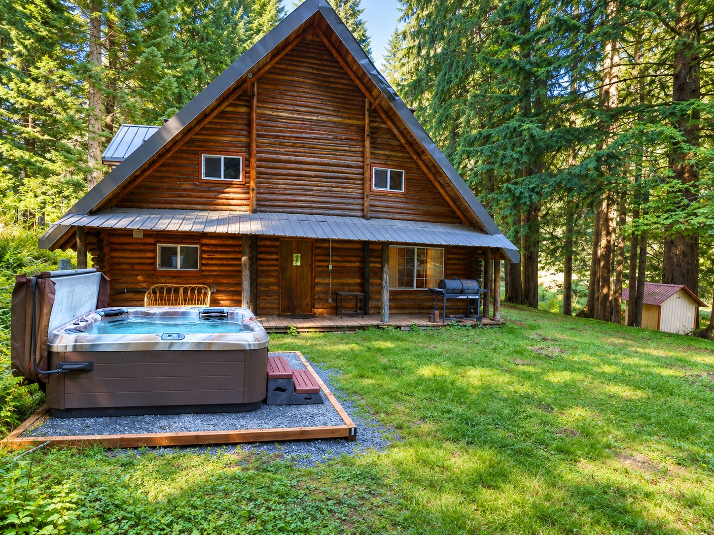 A log cabin with a hot tub and outdoor seating area surrounded by trees.