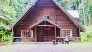Una cabaña de troncos con un porche delantero, una chimenea y un letrero que dice 'LOG CABIN'.