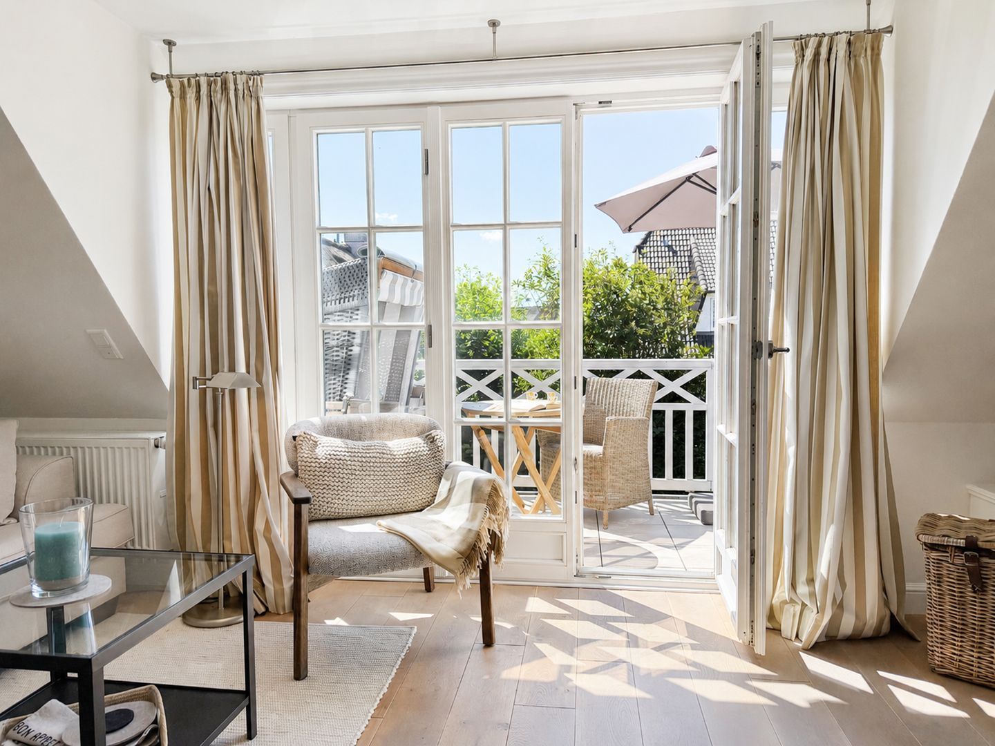 A room with a glass table, a sofa, and a view of the outside.