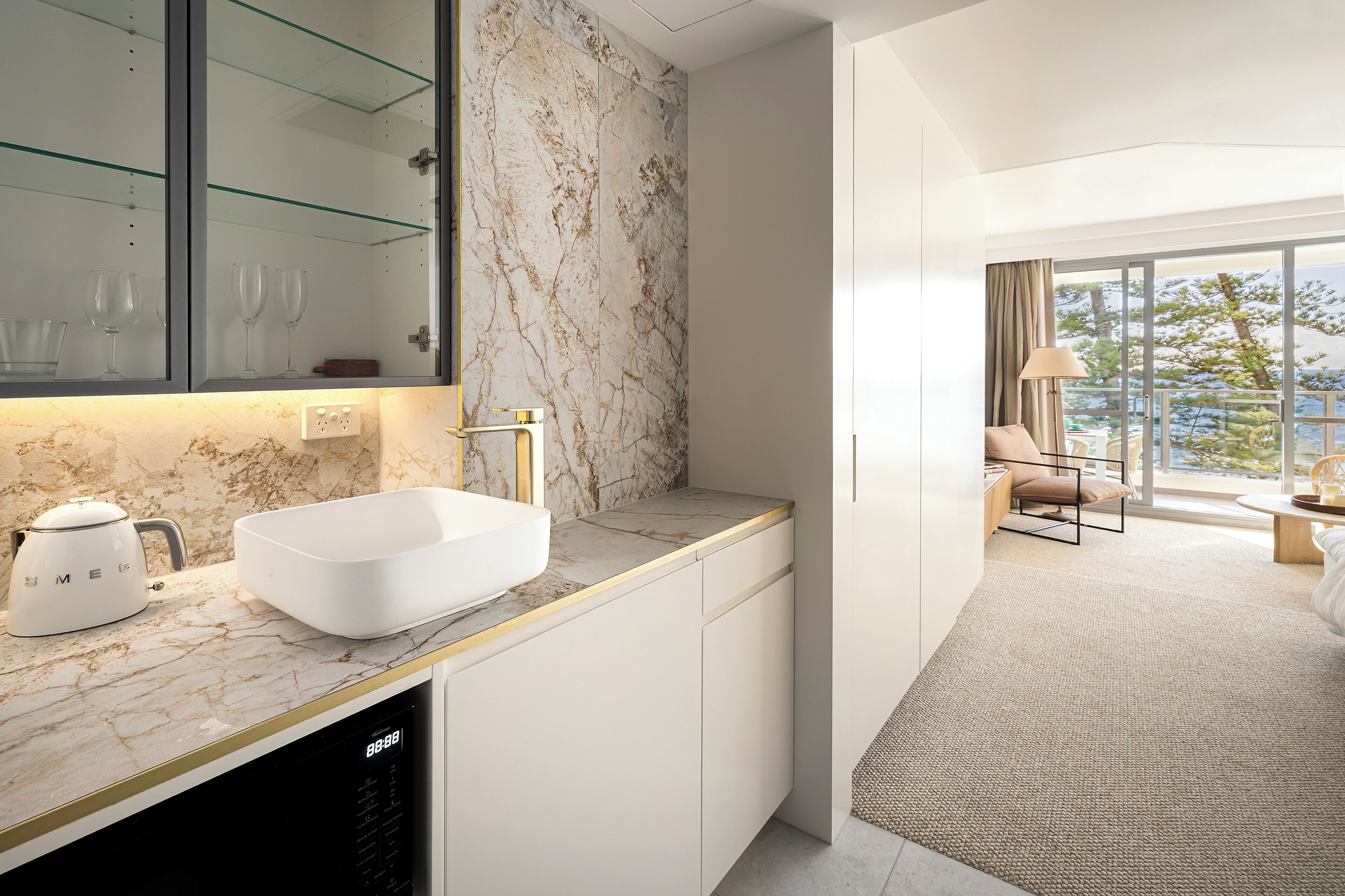 Ein modernes Badezimmer mit einem weißen Waschbecken, einer Marmor-Spritzschutzwand und einer Duschkabine aus Glas.