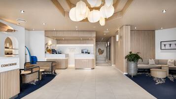 A modern hotel lobby with a reception desk, seating area, and a reception counter.