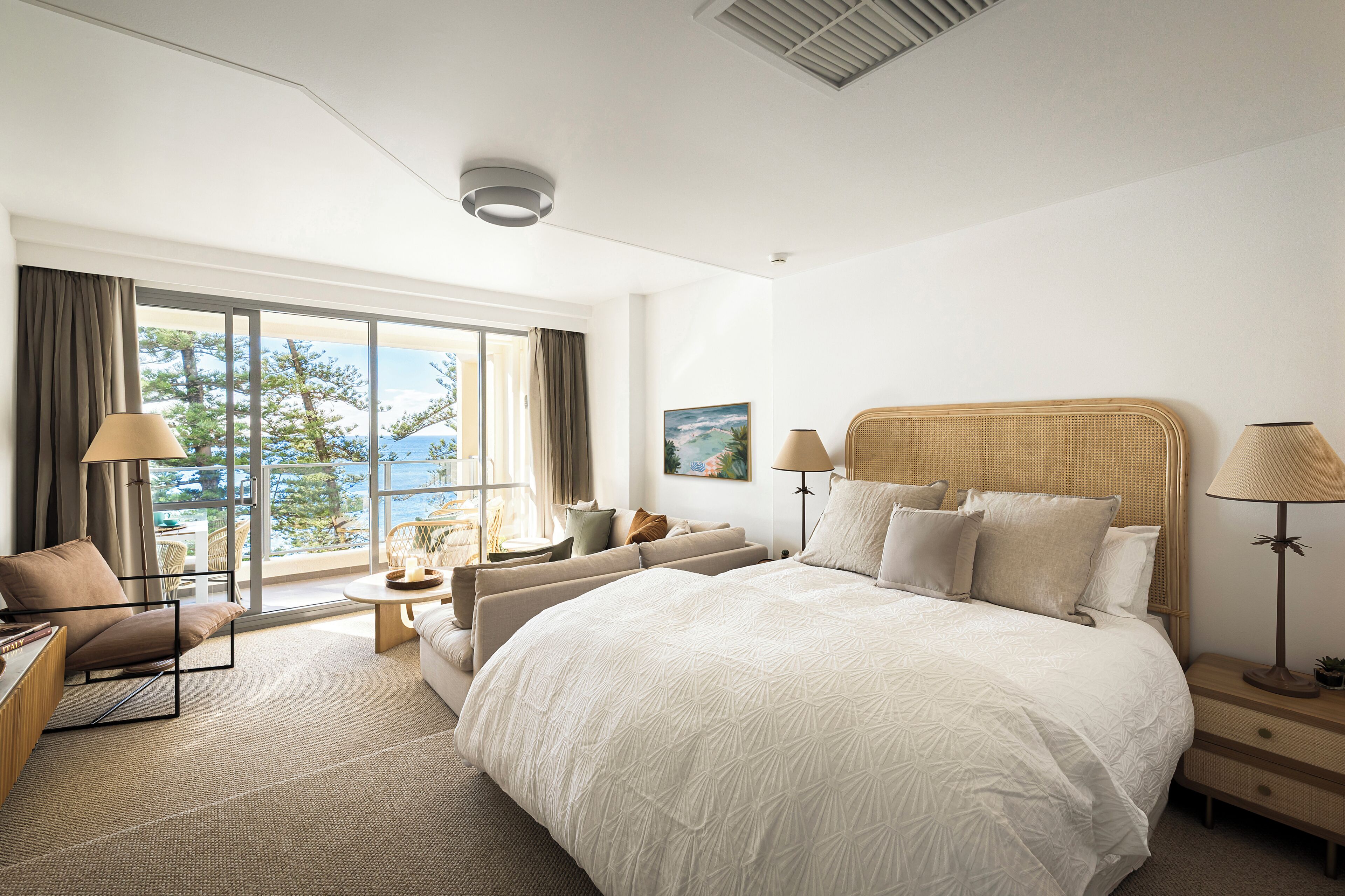 A hotel room with a large bed, a sofa, a chair, a table, and a view of the outdoors.