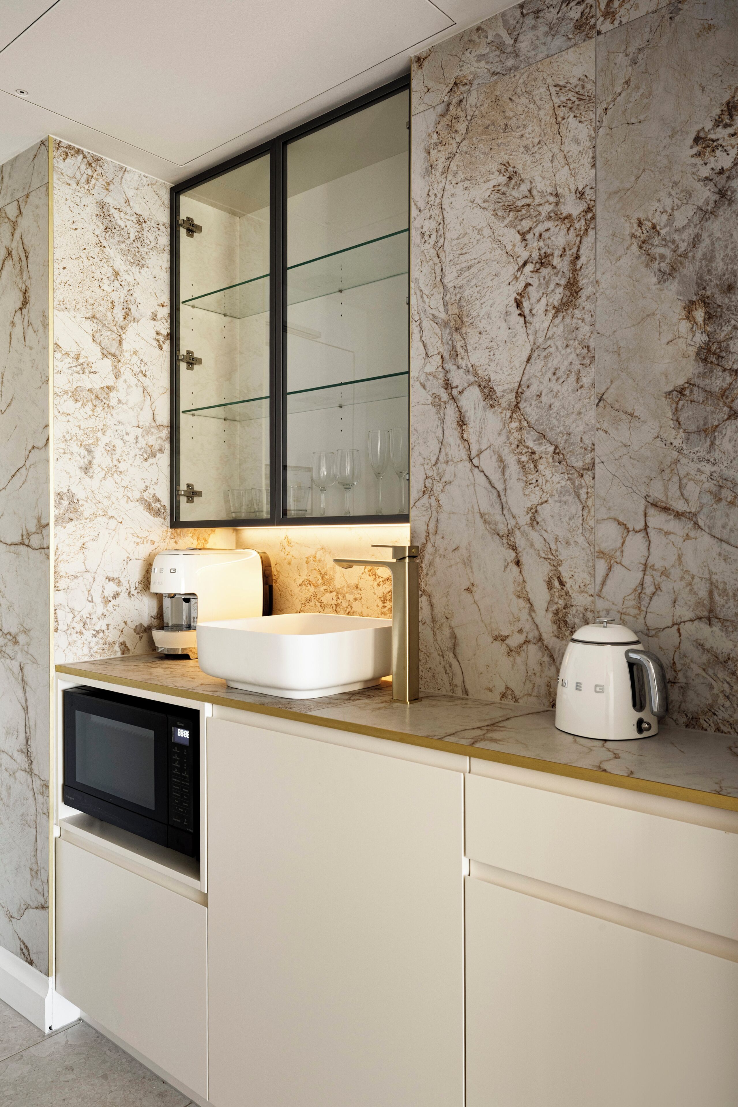 A modern kitchen with a built-in microwave, a white sink, and a coffee maker on the countertop.