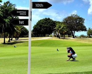 Een golfbaan met borden en een golfer in actie.