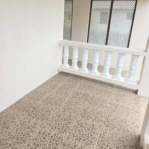 A balcony with a white balustrade and a tiled floor.