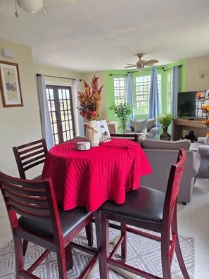 A dining area with a red tablecloth, wooden chairs, a ceiling fan, and a green wall. - Spacious 2BR Home with Private Parking & Large Patio. (Frere Pilgrim)