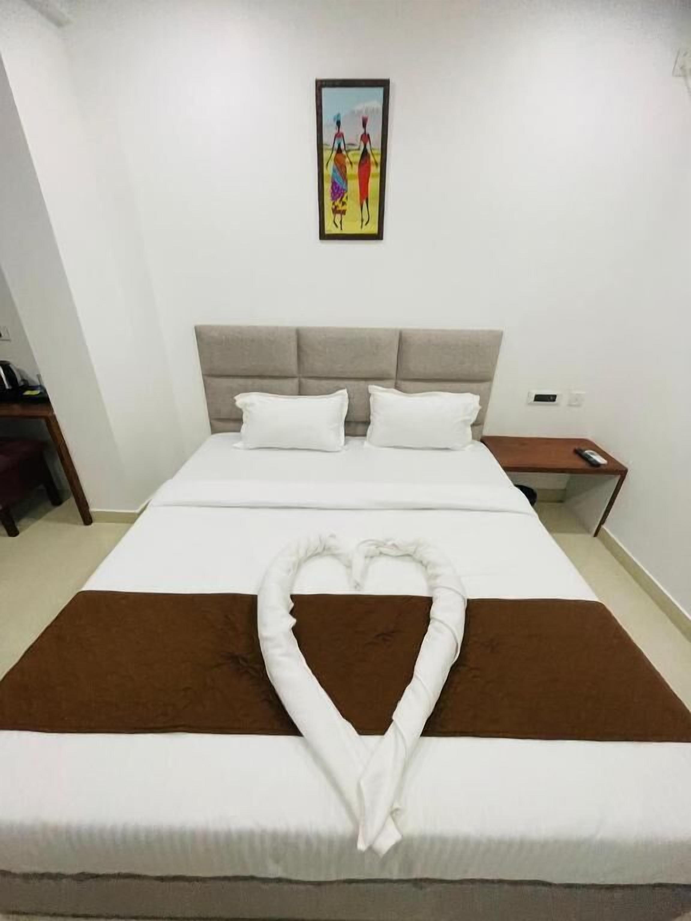 Una camera d'albergo con un letto, un comodino e un quadro appeso al muro.