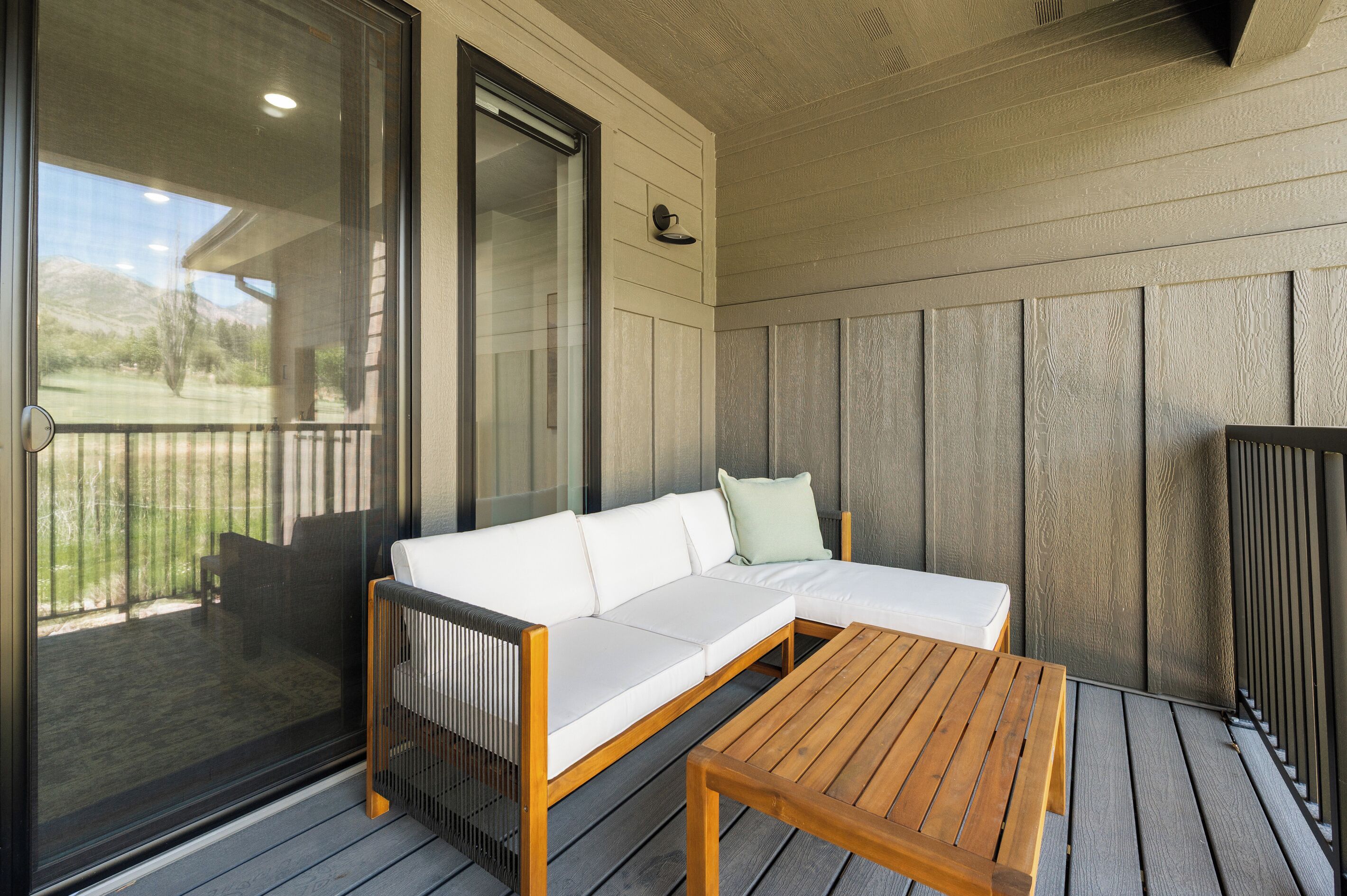 A covered outdoor seating area with a wooden table and a white sofa.