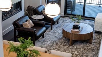 En moderne stue med en lædersofa, et rundt sofabord og en pejs.