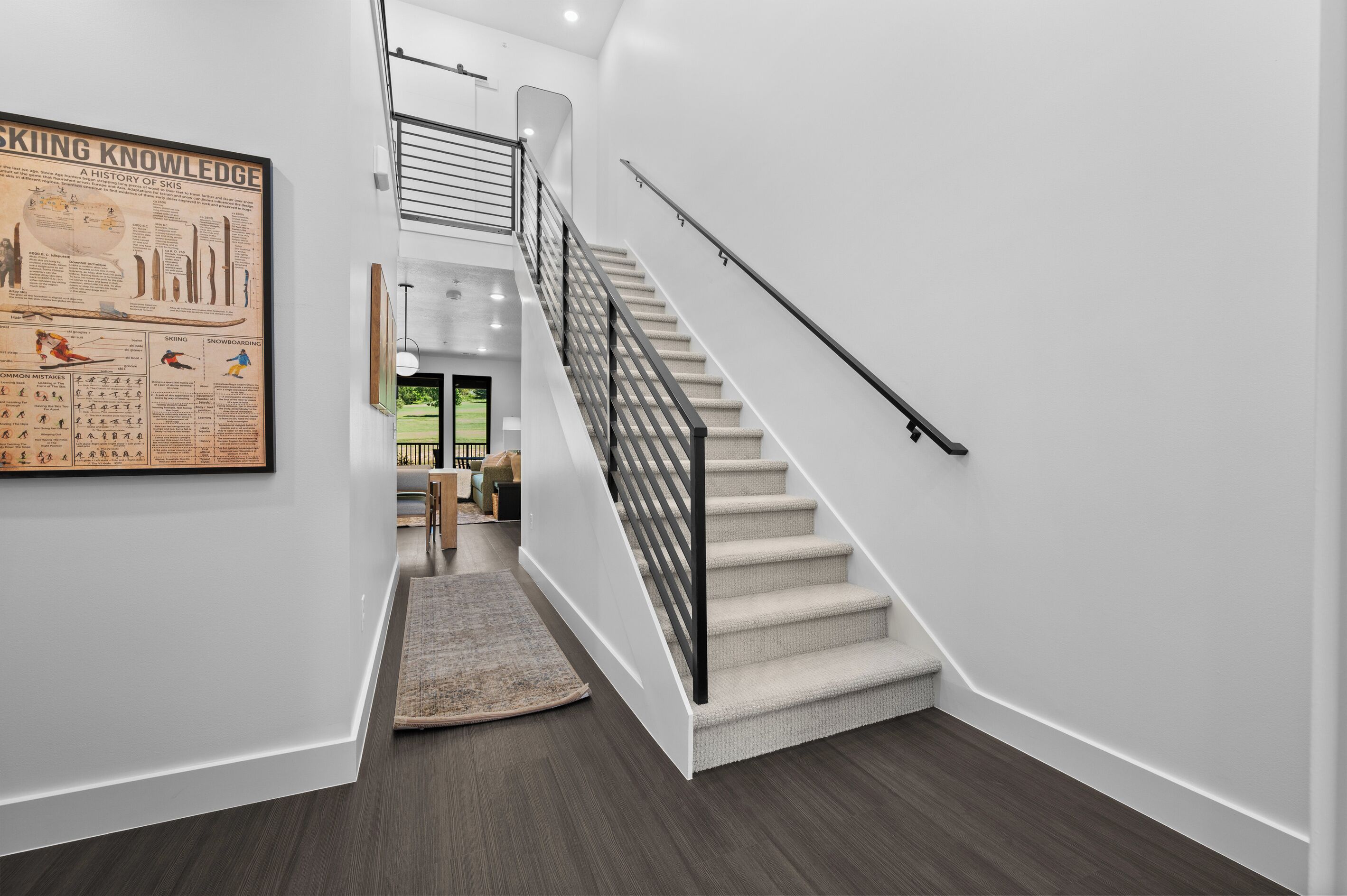 A modern interior with a staircase, a framed historical poster, and a rug.