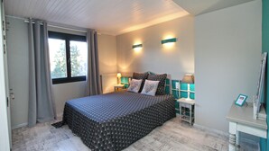 A bedroom with a bed, curtains, a window, two wall-mounted lamps, and a small table with a lamp. - COTTAGE IN THE GERARDMER AREA, SURROUNDED BY NATURE (Ban-sur-Meurthe-Clefcy)