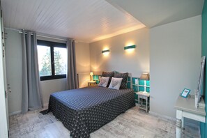 A bedroom with a bed, curtains, a window, two wall-mounted lamps, and a small table with a lamp. - COTTAGE IN THE GERARDMER AREA, SURROUNDED BY NATURE (Ban-sur-Meurthe-Clefcy)