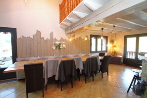 A restaurant with a long wooden table, chairs, and a decorative wall. - COTTAGE IN THE GERARDMER AREA, SURROUNDED BY NATURE (Ban-sur-Meurthe-Clefcy)