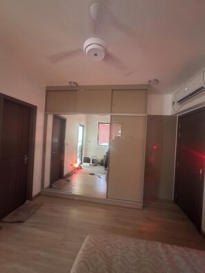 A room with a ceiling fan, a sliding door leading to another room, and an air conditioning unit on the wall. - 2-bedroom apartment in brilliant Malé with AC for relaxing stays (Malé)