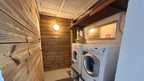 Ein Waschraum mit zwei Waschmaschinen mit Frontlader, einer Holzwand und einer Deckenleuchte.