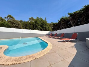 A swimming pool with a tiled deck and red lounge chairs. - Villa with a pool in the heart of Pyla-sur-Mer / La Teste-de-Buch / Arcachon (La Teste-de-Buch)