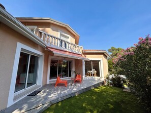 Uma casa com alpendre coberto, janelas amplas e gramado bem cuidado.