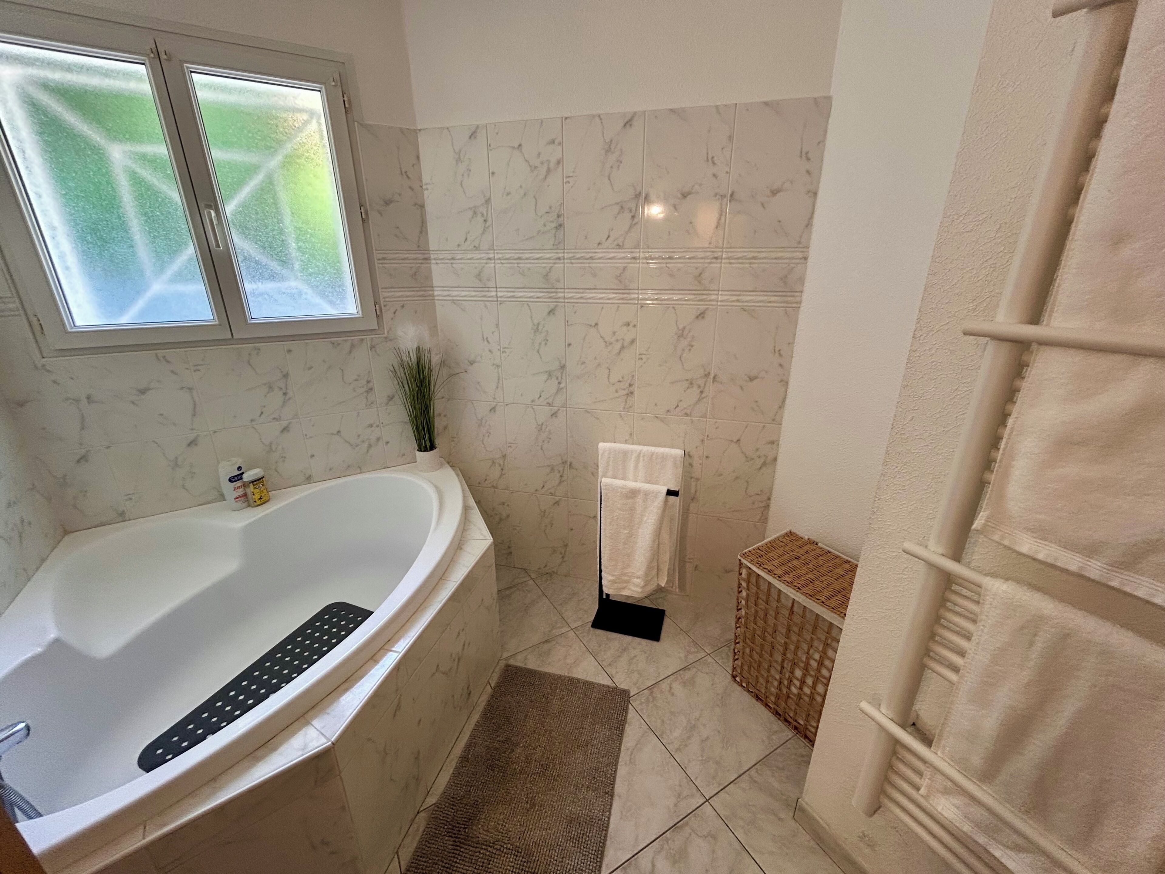 A bathroom with a bathtub, a shower, and a window.