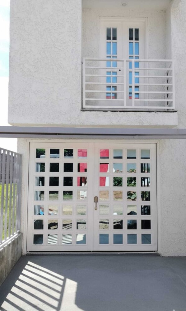 A white building with a large garage door and a balcony with a white railing.