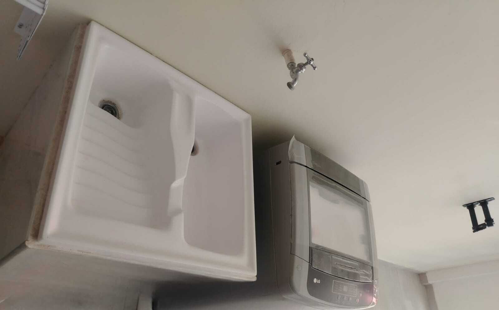 A bathroom with a white sink, a mirror, and a wall-mounted faucet.