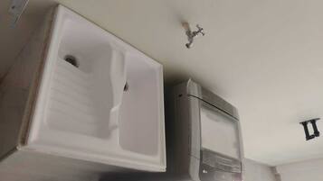 A bathroom with a white sink, a mirror, and a wall-mounted faucet.