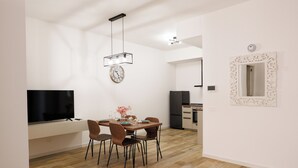Una cocina moderna con horno integrado y comedor con mesa y sillas de madera.