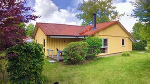 Ett gult hus med ett rött tak, en skorsten och en liten veranda.