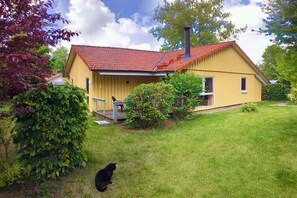 A yellow house with a red roof, a chimney, and a small porch. - Moderner Doppelbungalow mit Terrasse und Grill im Ferienpark Mirow (Granzow)