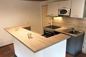 A compact kitchen with a central island, a microwave, an oven, and a sink. - Moderner Doppelbungalow mit Terrasse und Grill im Ferienpark Mirow (Granzow)