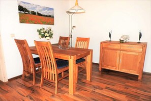 A wooden dining table with chairs, a lamp, and a cabinet with decorative items. - Moderner Doppelbungalow mit Terrasse und Grill im Ferienpark Mirow (Granzow)