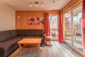 A cozy living area with a wooden floor, a sofa, a coffee table, and a painting on the wall. - Familienfreundlicher Doppelbungalow mit Terrasse im Ferienpark Mirow (Granzow)