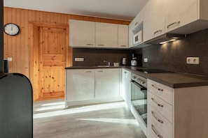 Eine moderne Küche mit Holzverkleidung, einem Backofen und einer Mikrowelle.