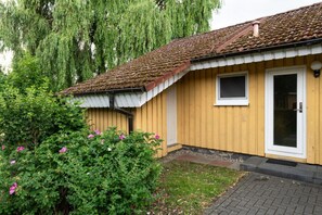 Ein Holzhaus mit Ziegeldach, einem kleinen Fenster und einer Tür.