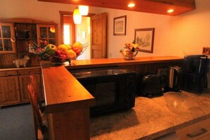 A kitchen with a wooden counter, a microwave, a kettle, and a fruit bowl. - Urlaub im Grünen - Doppelbungalow mit Terrasse im Ferienpark Mirow (Granzow)