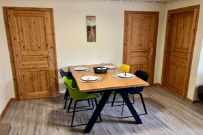 Ein Essbereich mit Holztisch, vier Stühlen und einem kleinen Bild an der Wand.