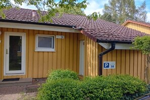 Ein Gebäude aus Holz mit einem Ziegeldach, einer Tür und einem Fenster. Ein Parkschild mit der Nummer 38 ist sichtbar.