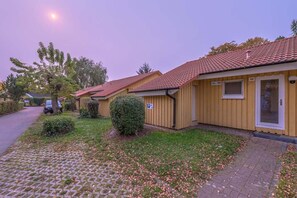 A row of yellow buildings with red roofs, each with a small window and a door. - Skandinavischer Doppelbungalow mit Terrasse im Ferienpark Mirow (Granzow)