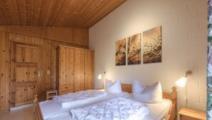 Ein Zimmer mit Holzwänden, einem Bett, Nachttischen und Kunstwerken an der Wand.
