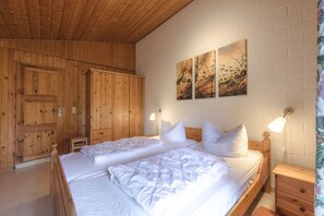 A wooden-paneled room with a bed, bedside tables, and artwork on the wall. - Doppelbungalow im skandinavischen Stil mit Terrasse im Ferienpark Mirow (Granzow)