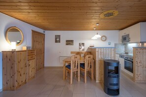 A wooden interior with a dining table, chairs, a stove, and a microwave. - Doppelbungalow im skandinavischen Stil mit Terrasse im Ferienpark Mirow (Granzow)
