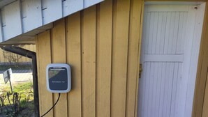 Una estación de carga para vehículos eléctricos instalada en una pared exterior de madera, con la etiqueta 'SKODA iV'.