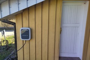 Eine an der Wand montierte Ladestation für Elektrofahrzeuge mit der Aufschrift 'SKODA iV' an einer Holzwand im Außenbereich.