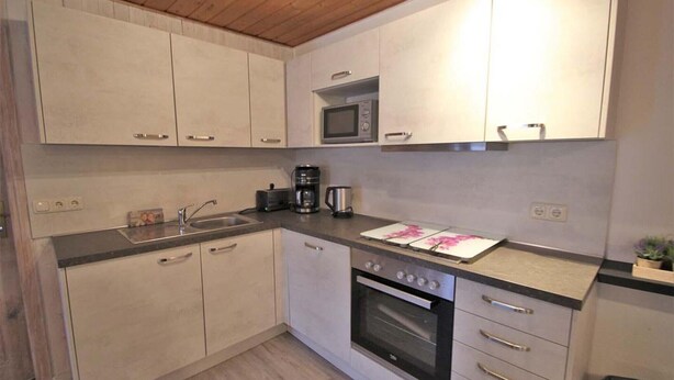 Una cocina equipada con microondas, horno, cafetera y pileta.