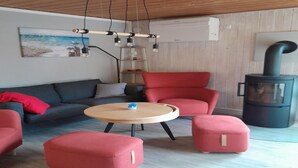 Una sala de estar moderna con sofá, sillones, una mesa redonda y una estufa de leña.